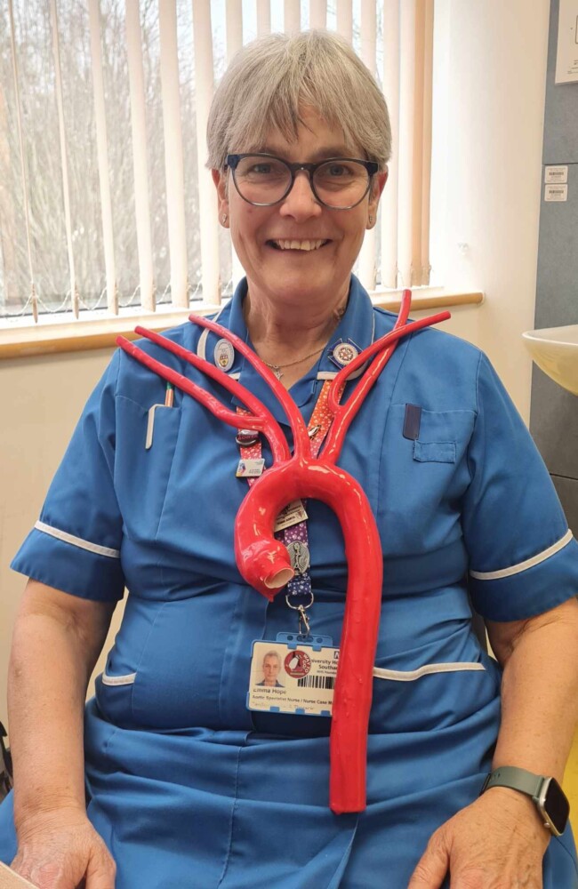 Emma Hope sitting on a chair in her aortic nurse uniform